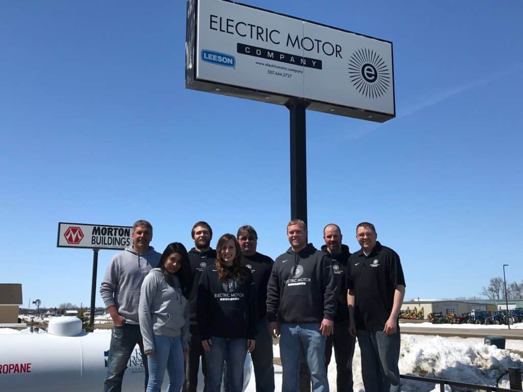 Electric Motor Company Staff infront of sign